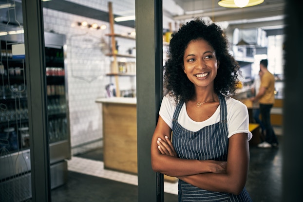 woman in apron standing outside cafe