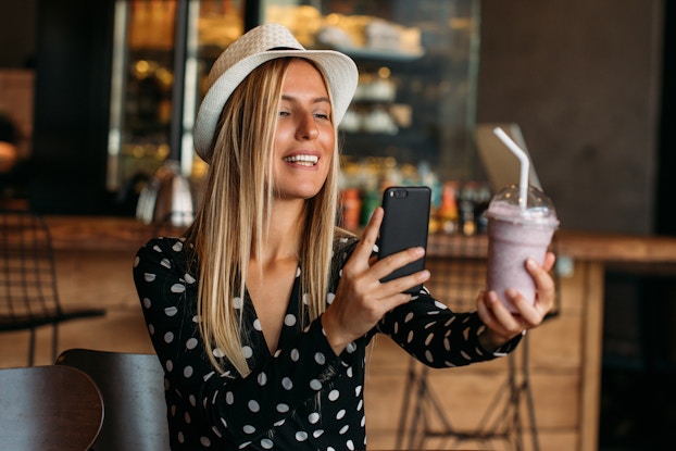  woman taking picture of milkshake with phone