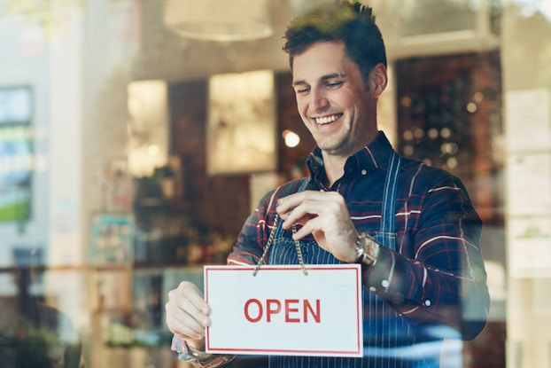 man holding an open sign in a window