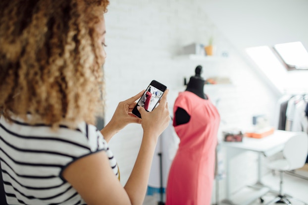  woman seamstress taking photo of dress on a mannequin