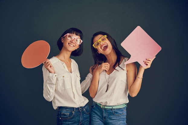 two women holding cutouts of speech boxes
