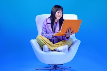  Woman sitting on a chair looking at a laptop. 