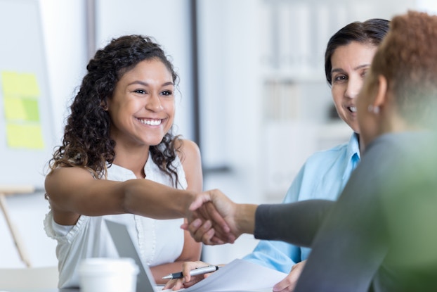  Smiling young professional woman shakes hands with her new employer.