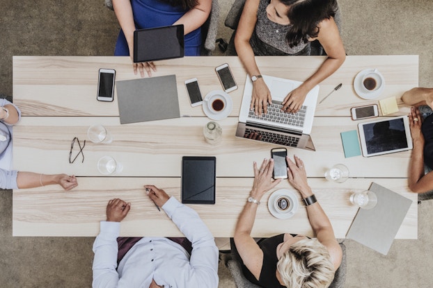 top view of coworkers sitting around a table