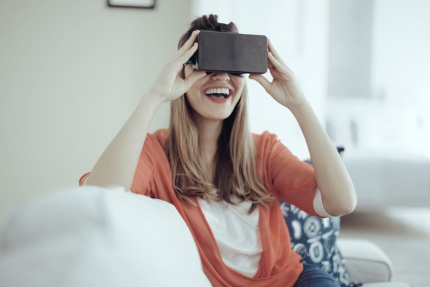     Young woman uses head-mounted virtual reality goggles.