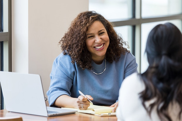  A businesswoman smiles encouragingly during a job interview at a female applicant.