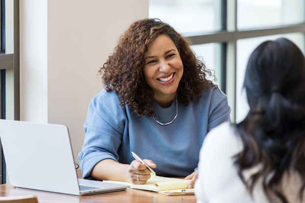 A businesswoman smiles encouragingly during a job interview at a female applicant.