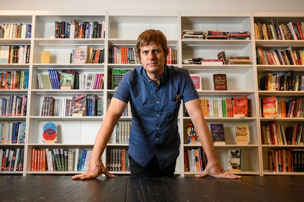  Andy Hunter, CEO, Bookshop.org, in front of bookshelves of books.