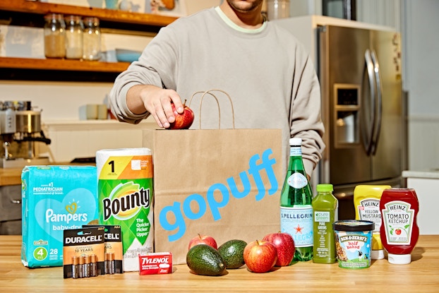 Person in their kitchen unloading groceries from a Gopuff shopping bag.