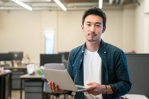 Portrait of young professional man in a modern office looking at the viewer.