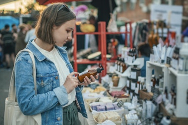  Shopper exploring label on organic body care goods at an open-air market with zero waste concept 