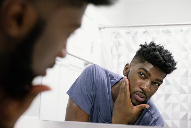 man checking his face in the mirror