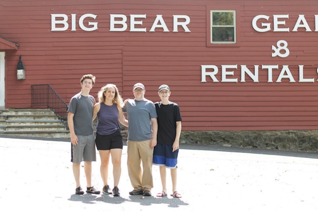  Group of people stand outside a outdoor equipment storefront