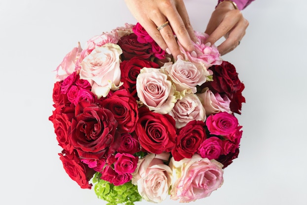 Top view of a person's hands putting together a floral arrangement from Bouquet Box.