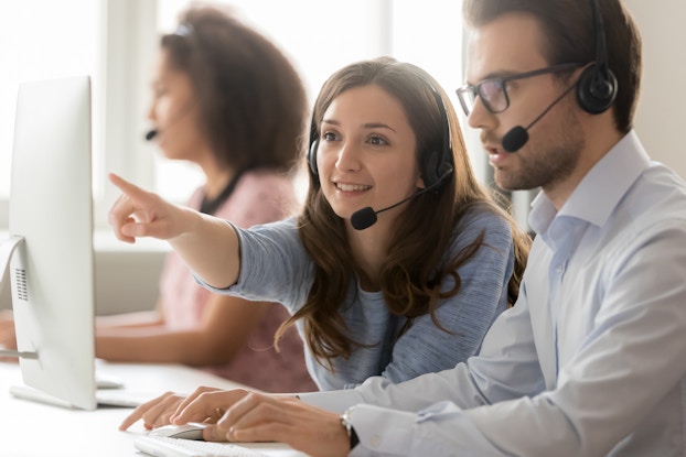 two coworkers on headsets and computers