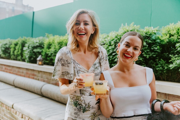  two women smiling holding margaritas