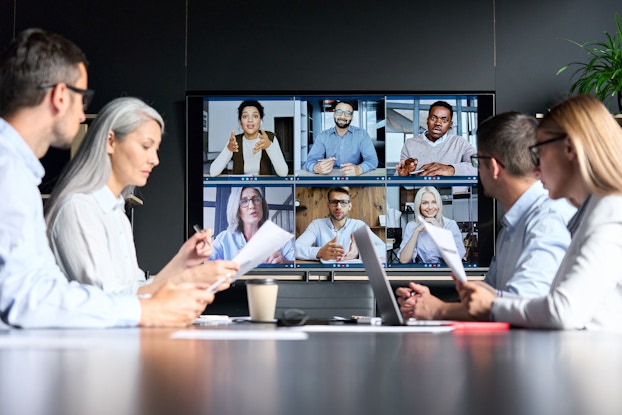  Meeting with some employees on videoconference and others in modern meeting room.