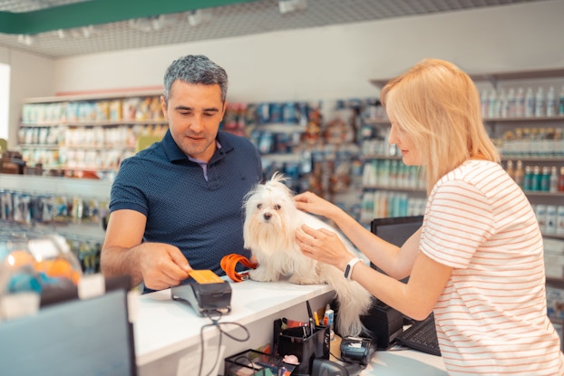 Grey-haired man paying for purchase with credit card in a shop.