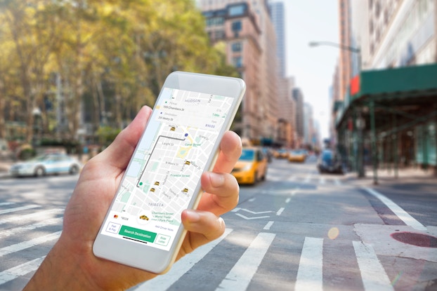 Person's hand holding a phone that display's the Curb taxi-hailing app.