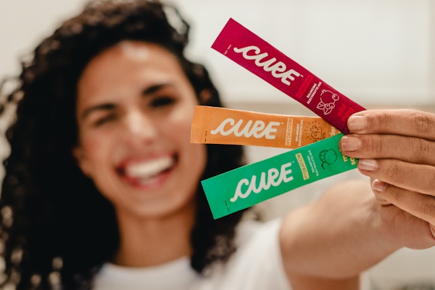 woman smiling holding up cure hydration drink packets