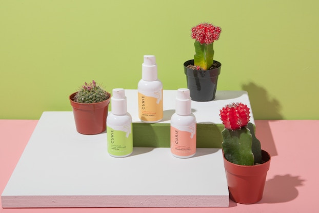 Product display of hand sanitizers by Curie on a countertop with potted succulent plants.