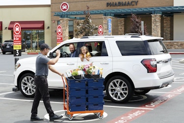  Albertsons employee delivering groceries to a customer and their child in their car. 