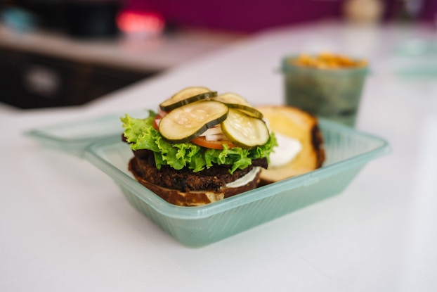 Open-faced burger and other food inside reusable containers by Deliver Zero.