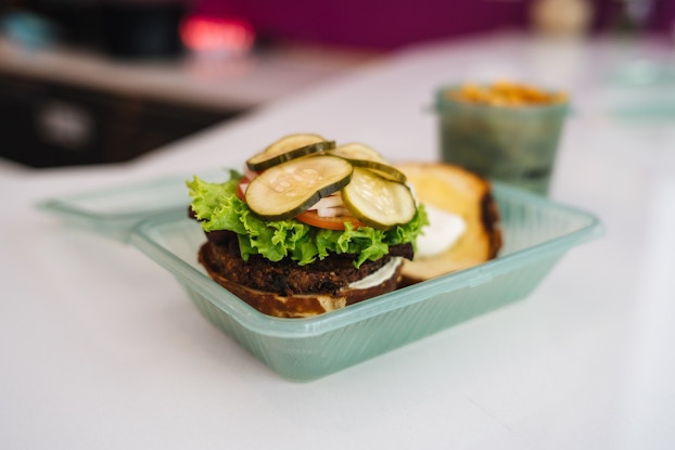  Open-faced burger and other food inside reusable containers by Deliver Zero.