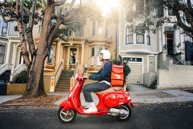 DoorDash employee delivering a last-mile parcel on a scooter.