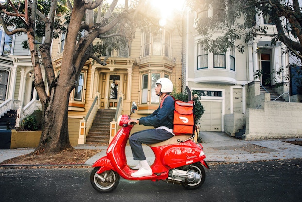  DoorDash employee delivering a last-mile parcel on a scooter.