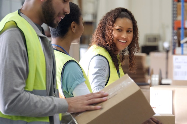  People working inside a shipping room packing boxes.