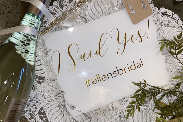  "I Said Yes!" sign with bridal earrings and a champagne bottle courtesy of Ellen's Bridal and Dress Shop.