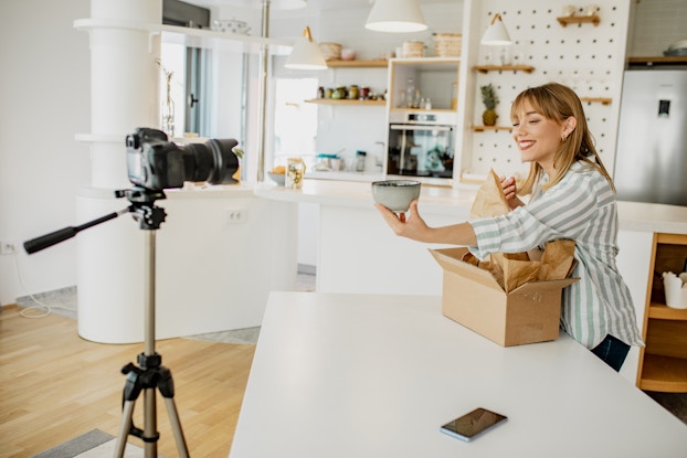 Pottery artist creates a video of her packing a product in a clean, brightly lit room.