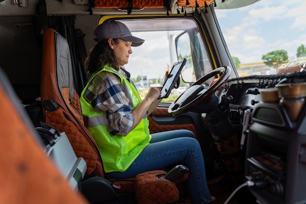 A woman truck driver sets up her navigation GPS equipment to reach her destination and deliver goods.
