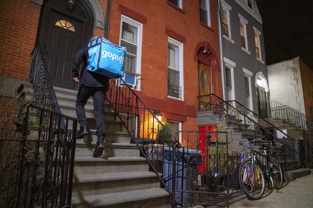  Gopuff delivery person bringing groceries to someone's doorstep.