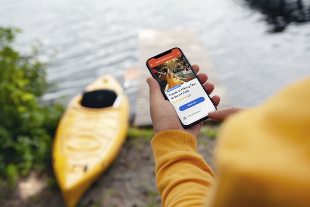  Person holding a phone by a lake looking at the GetYourGuide app.