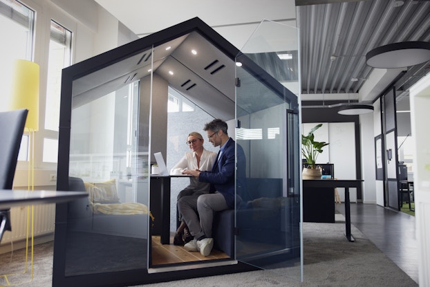 Office workers on a call in a telephone booth
