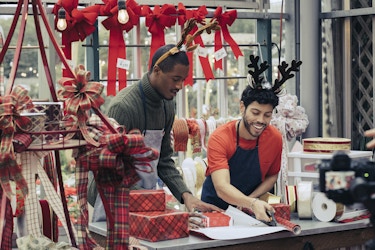  Two people working in their shop with Christmas decorations around. 