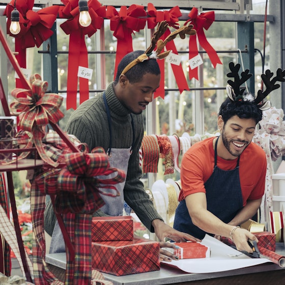 Two people working in their shop with Christmas decorations around.