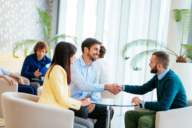  Two businessmen shake hands at a meeting.