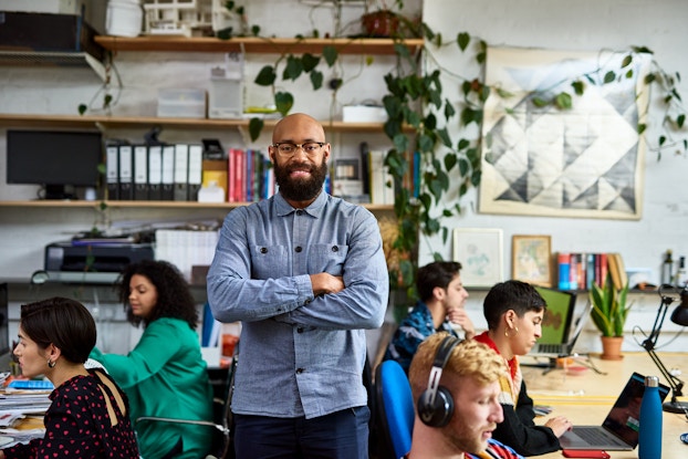Black business owner smiling with employees behind him