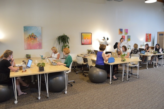  People working at desks inside a Hera Hub coworking space.