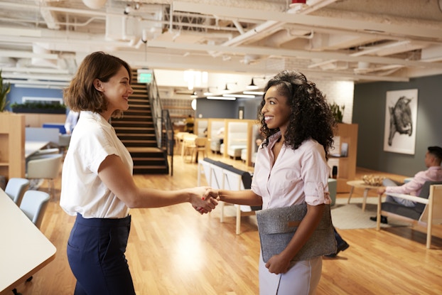  Two businesswomen meeting and shaking hands in modern office