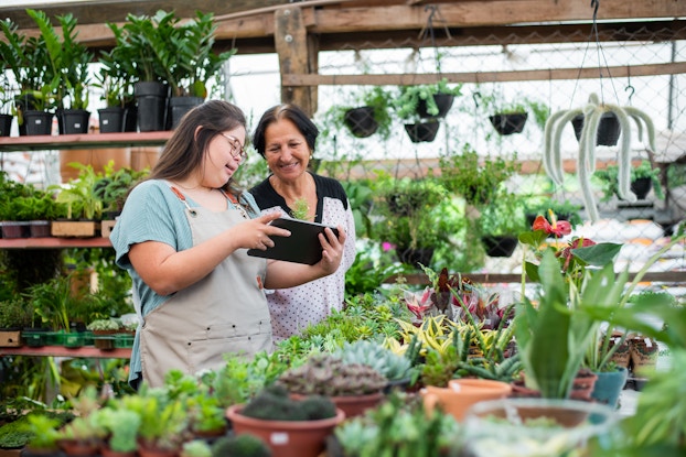 Two shop employees check inventory on a tablet.