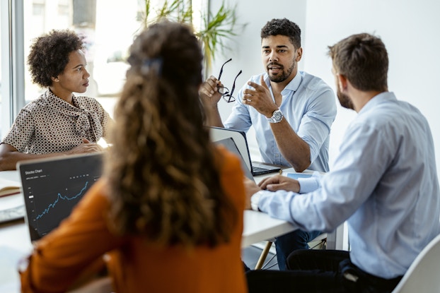 Colleagues meet and have a collaborative discussion in an office conference room.