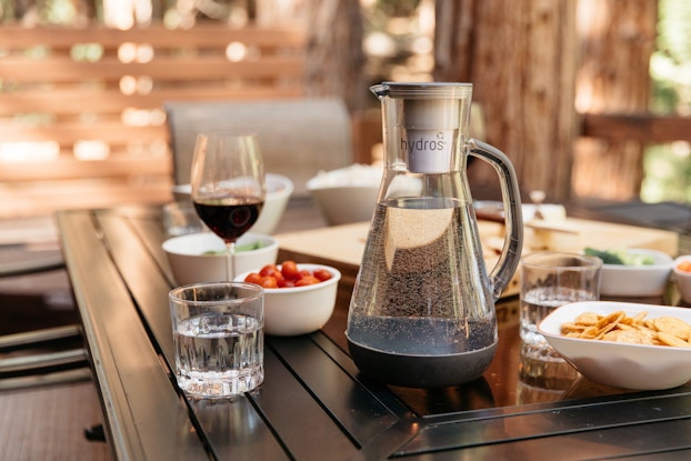Hydros water pitcher on a table with plates of food and snacks.