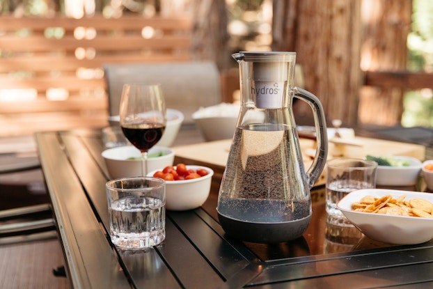  Hydros water pitcher on a table with plates of food and snacks.