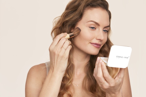  Model applying Jane Iredale cosmetics to her face.
