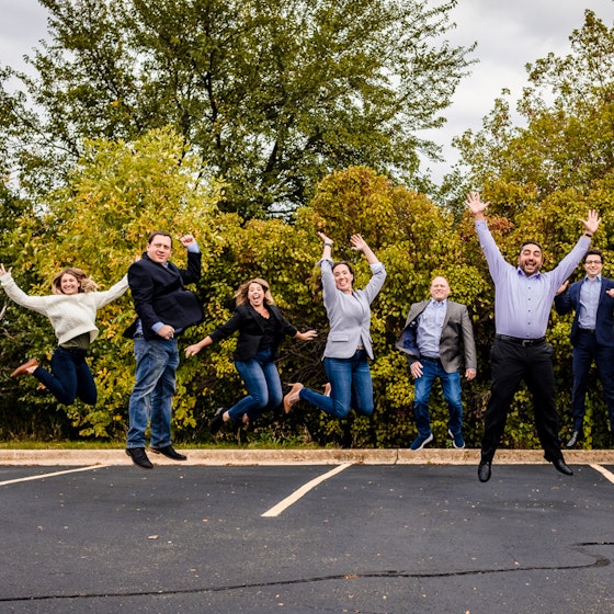 Business people pose happily in a parking lot