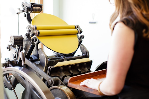 danielle chargo, owner of iron leaf press, working on machine